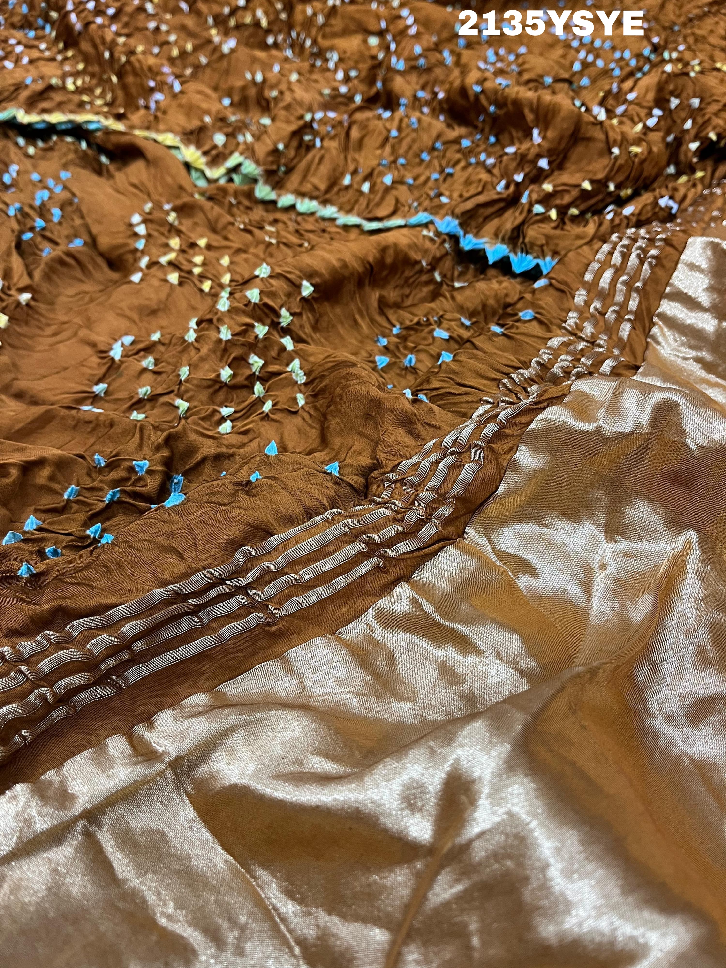 A brown and yellow silk saree with bandhani style dots and a metallic border.