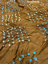A brown and yellow silk saree with bandhani style dots and a metallic border.