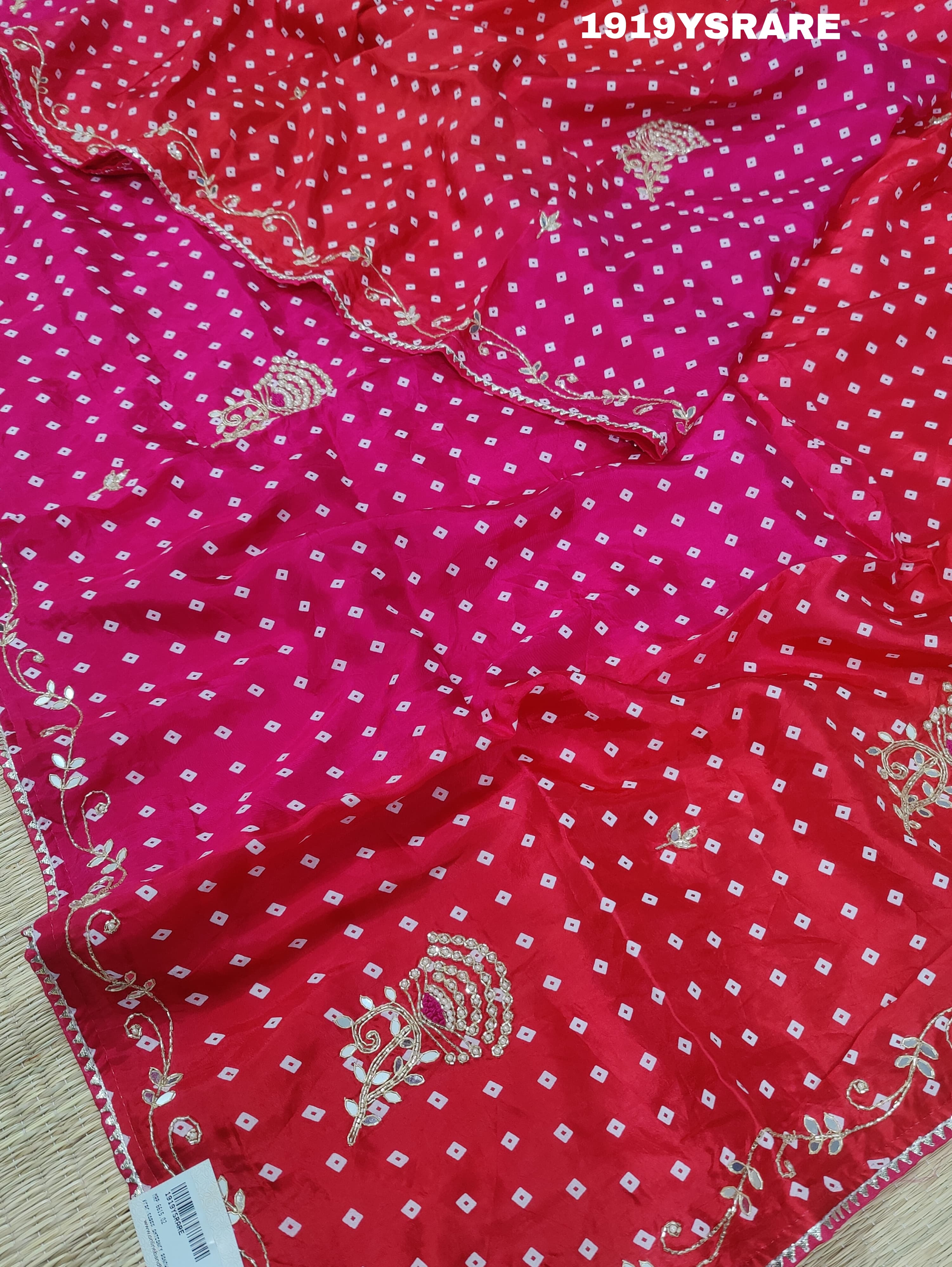 A saree with a bandhani pattern and cutdana work, predominantly pink with red accents.
