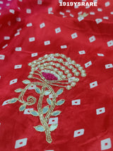 A saree with a bandhani pattern and cutdana work, predominantly pink with red accents.
