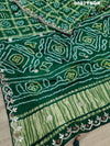 A green and silver pure gaji silk saree with bandhani pattern and gotapatti handwork, displayed on a surface.