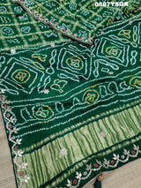 A green and silver pure gaji silk saree with bandhani pattern and gotapatti handwork, displayed on a surface.