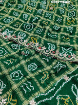 A green and silver pure gaji silk saree with bandhani pattern and gotapatti handwork, displayed on a surface.