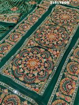 A green saree with red bandhej patterns and royal aari work, along with real mirror work on the border.