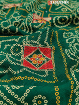 A green saree with red bandhej patterns and royal aari work, along with real mirror work on the border.