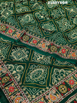 A green bandhej saree with royal aari and real mirror work, displayed on a surface.