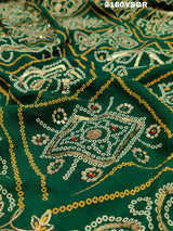 A green bandhej saree with royal aari and real mirror work, displayed on a surface.