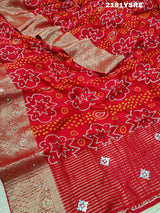 A red and silver bandhani style silk saree with mirror handwork, including floral patterns and a traditional design.