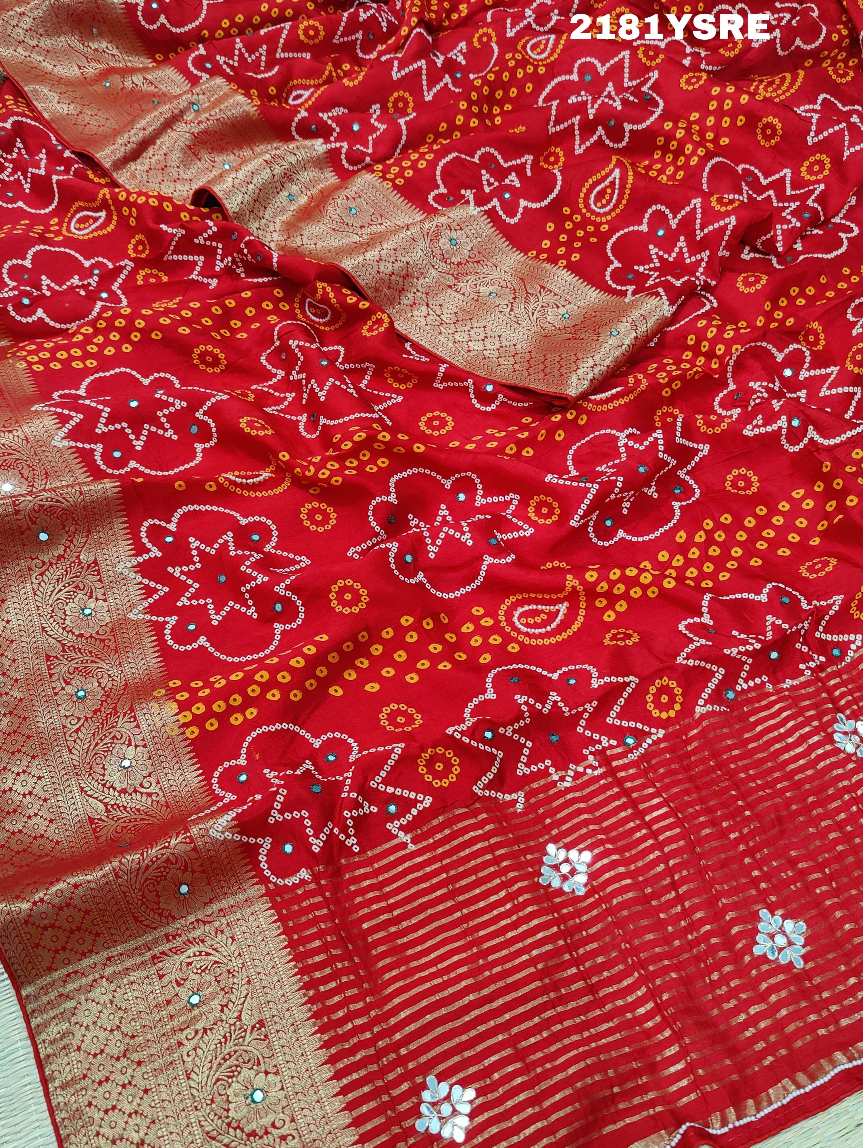 A red and silver bandhani style silk saree with mirror handwork, including floral patterns and a traditional design.