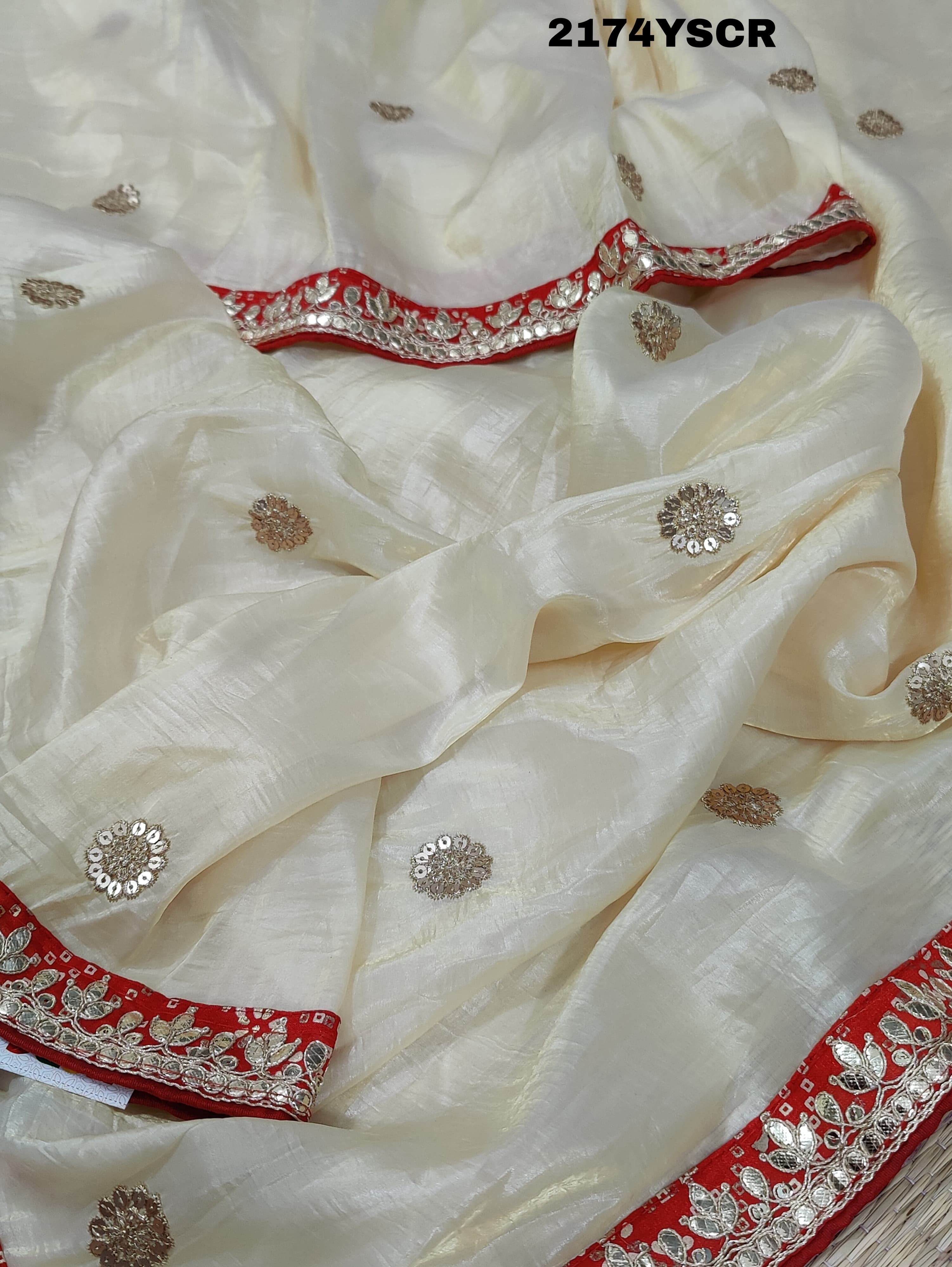 A red and white tissue silk saree with Bollywood style embellishments and gotapatti work.