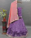 A traditional wear lehenga in purple with detailed embroidery and a pink dupatta.