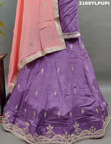 A traditional wear lehenga in purple with detailed embroidery and a pink dupatta.