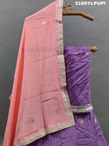 A traditional wear lehenga in purple with detailed embroidery and a pink dupatta.