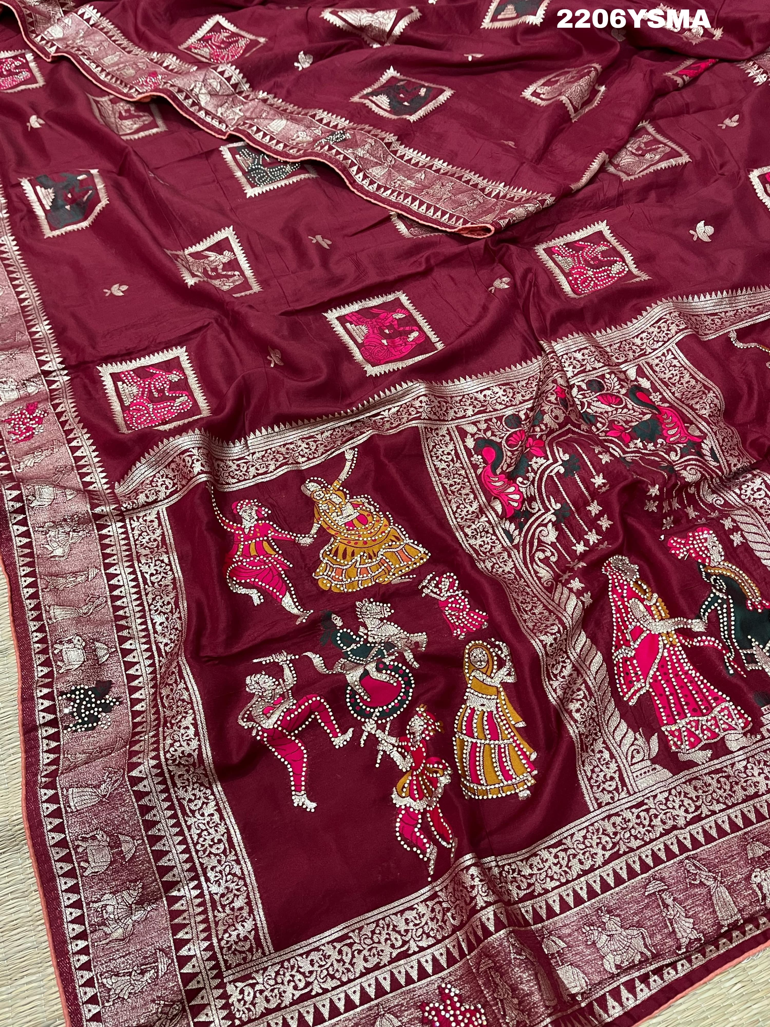 A wine colored Dola Silk saree with Banarasi style stone work, depicting traditional Indian motifs and characters.