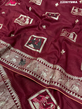 A wine colored Dola Silk saree with Banarasi style stone work, depicting traditional Indian motifs and characters.