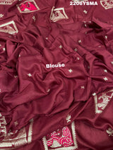 A wine colored Dola Silk saree with Banarasi style stone work, depicting traditional Indian motifs and characters.