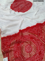 A traditional saree with red and white colors and intricate patterns, predominantly red at one end with a floral design.