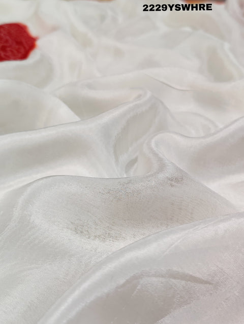 A traditional saree with red and white colors and intricate patterns, predominantly red at one end with a floral design.