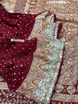 A maroon and gold saree with intricate geometric bandhej patterns and gotapatti handwork.