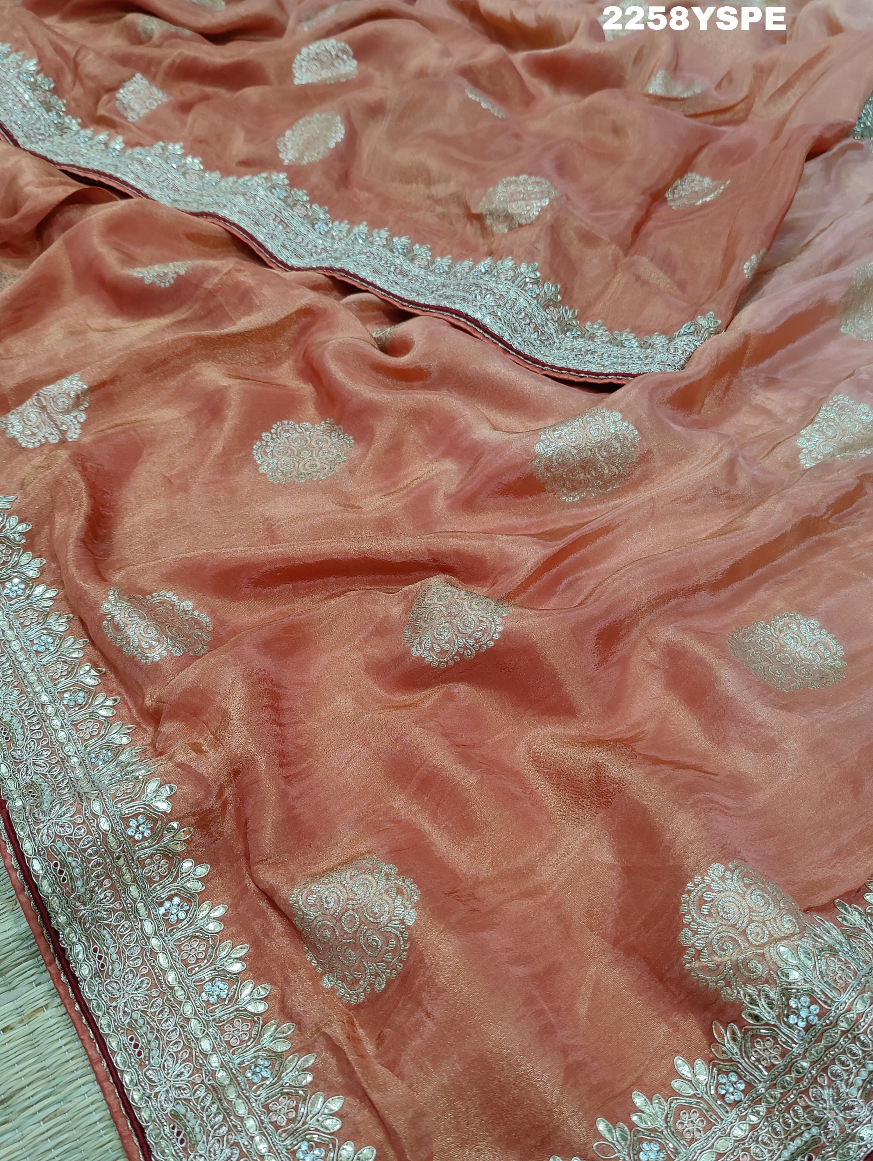 A peach-colored Banarasi silk saree with Bollywood-style embellishments including sequins and gotapatti work, 