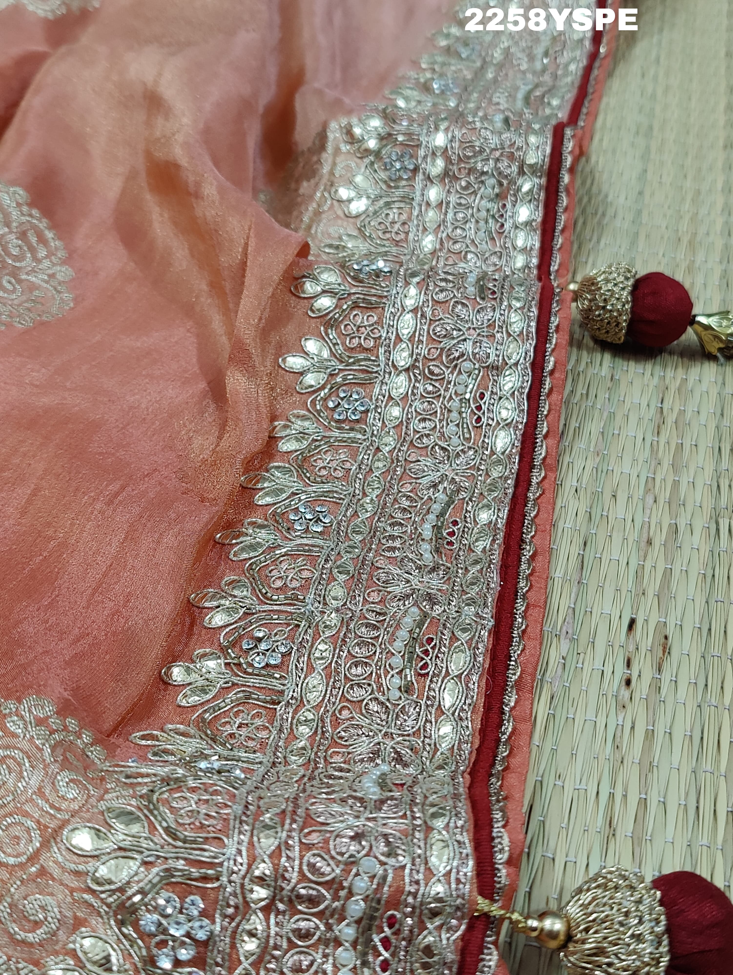 A peach-colored Banarasi silk saree with Bollywood-style embellishments including sequins and gotapatti work, 