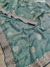 A sea green Banarasi silk saree with Bollywood style embellishments including sequins and gotapatti work