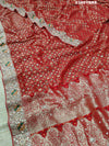 A red Banarasi style saree with gotapatti work, showcasing the detailed embroidery and pattern.