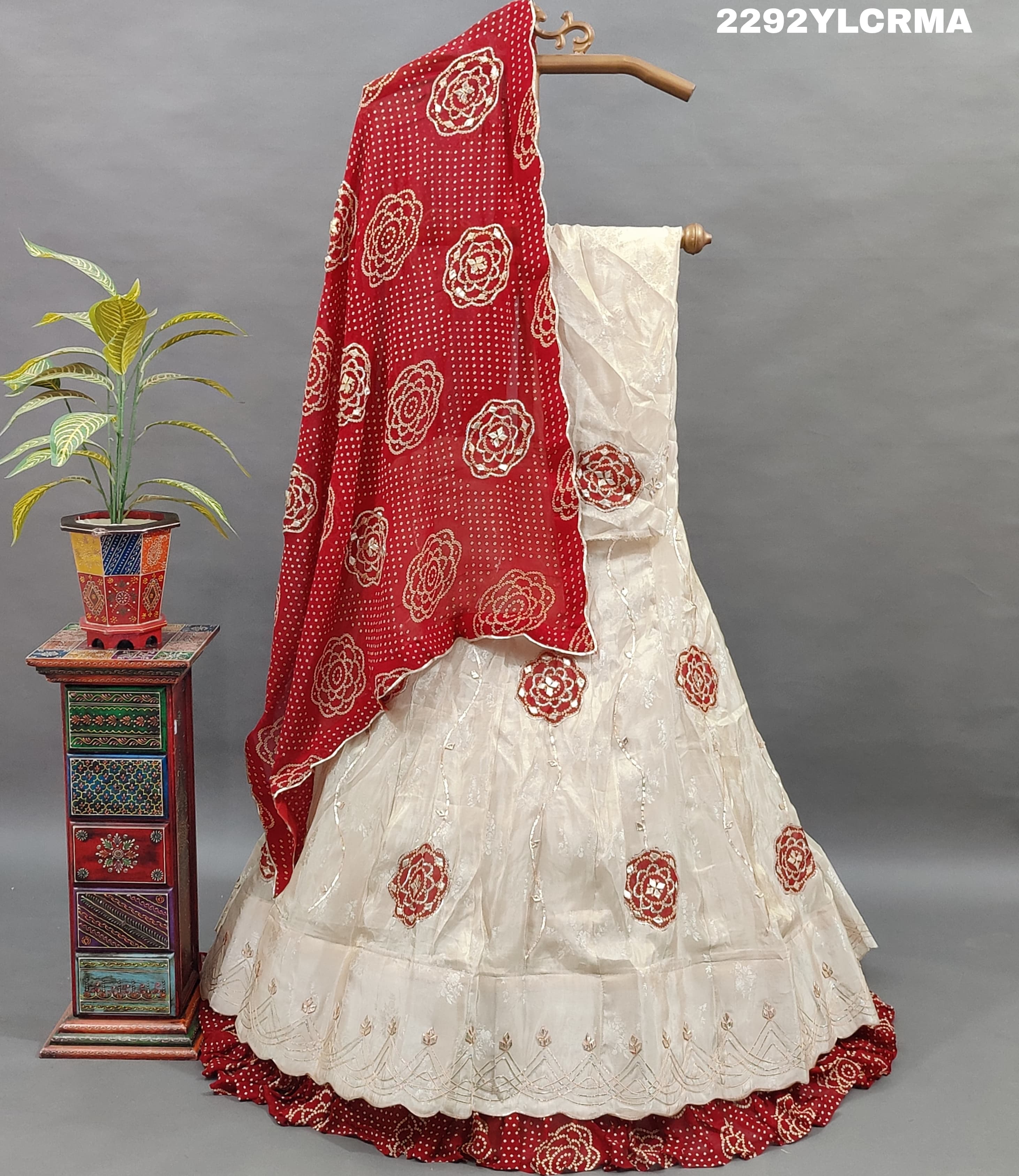 A traditional Indian lehenga with bandhani style patterns in cream and maroon colors