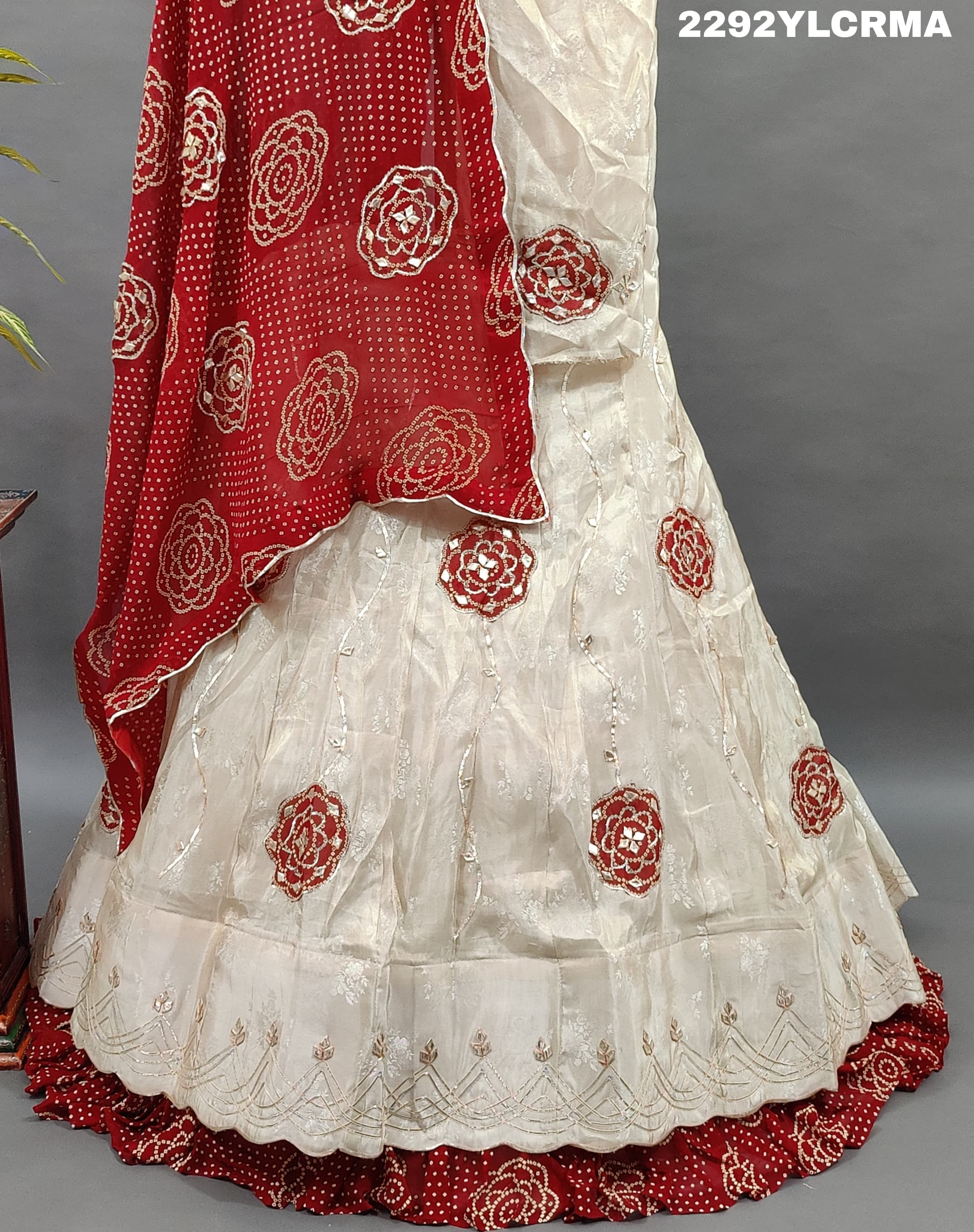 A traditional Indian lehenga with bandhani style patterns in cream and maroon colors
