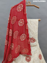 A traditional Indian lehenga with bandhani style patterns in cream and maroon colors