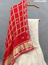 A cream-colored Lehenga with red and gold Gota patti Work 
