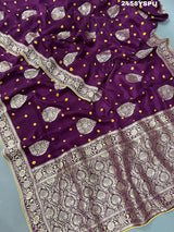 A purple Dola silk saree with detailed Zari weaving work and a Banarasi style pattern, including a wide border with similar ornate design.