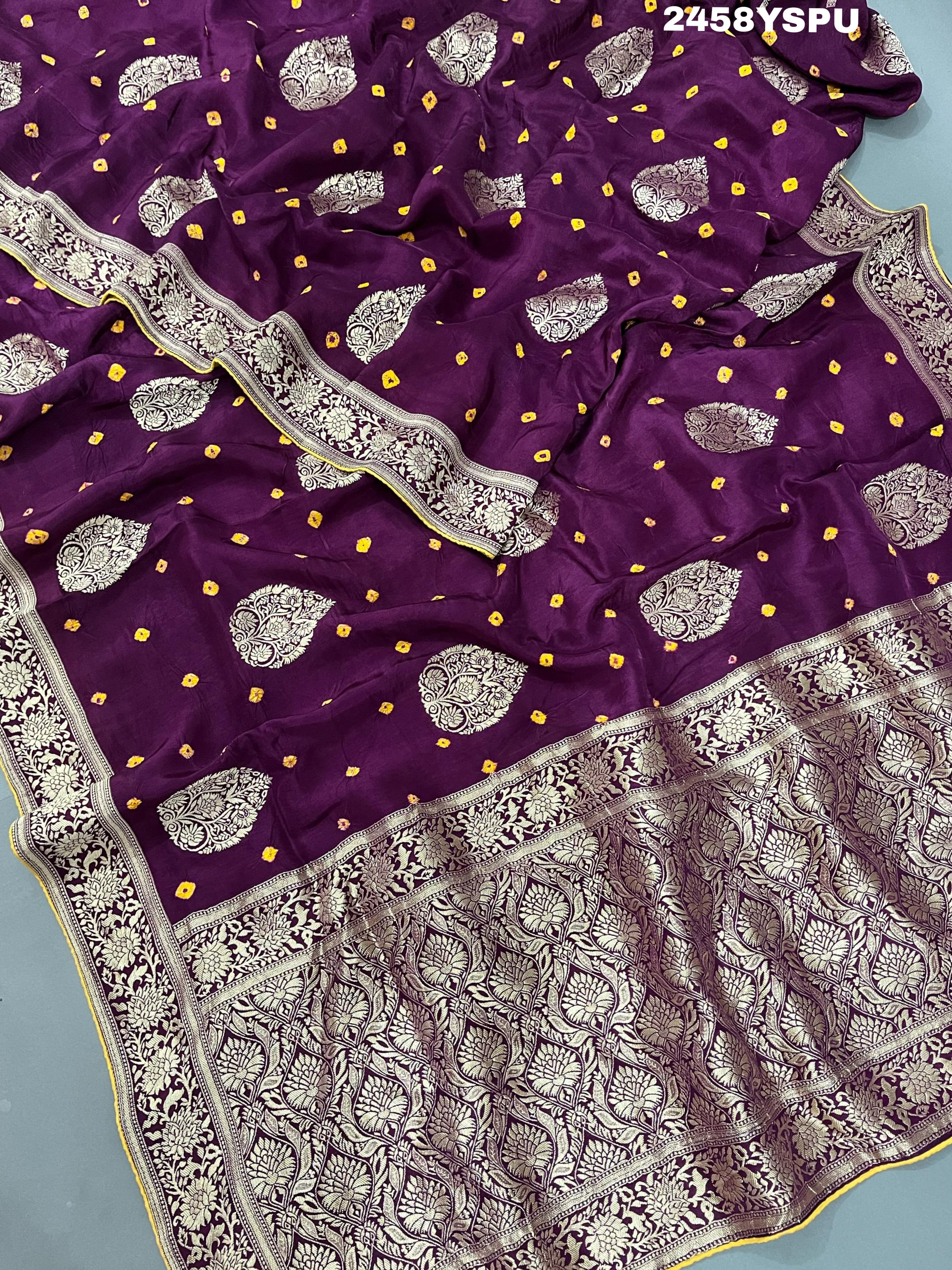 A purple Dola silk saree with detailed Zari weaving work and a Banarasi style pattern, including a wide border with similar ornate design.