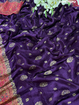 A purple and red Dola silk Banarasi saree with cutdana work, captured with a floral design at the border.