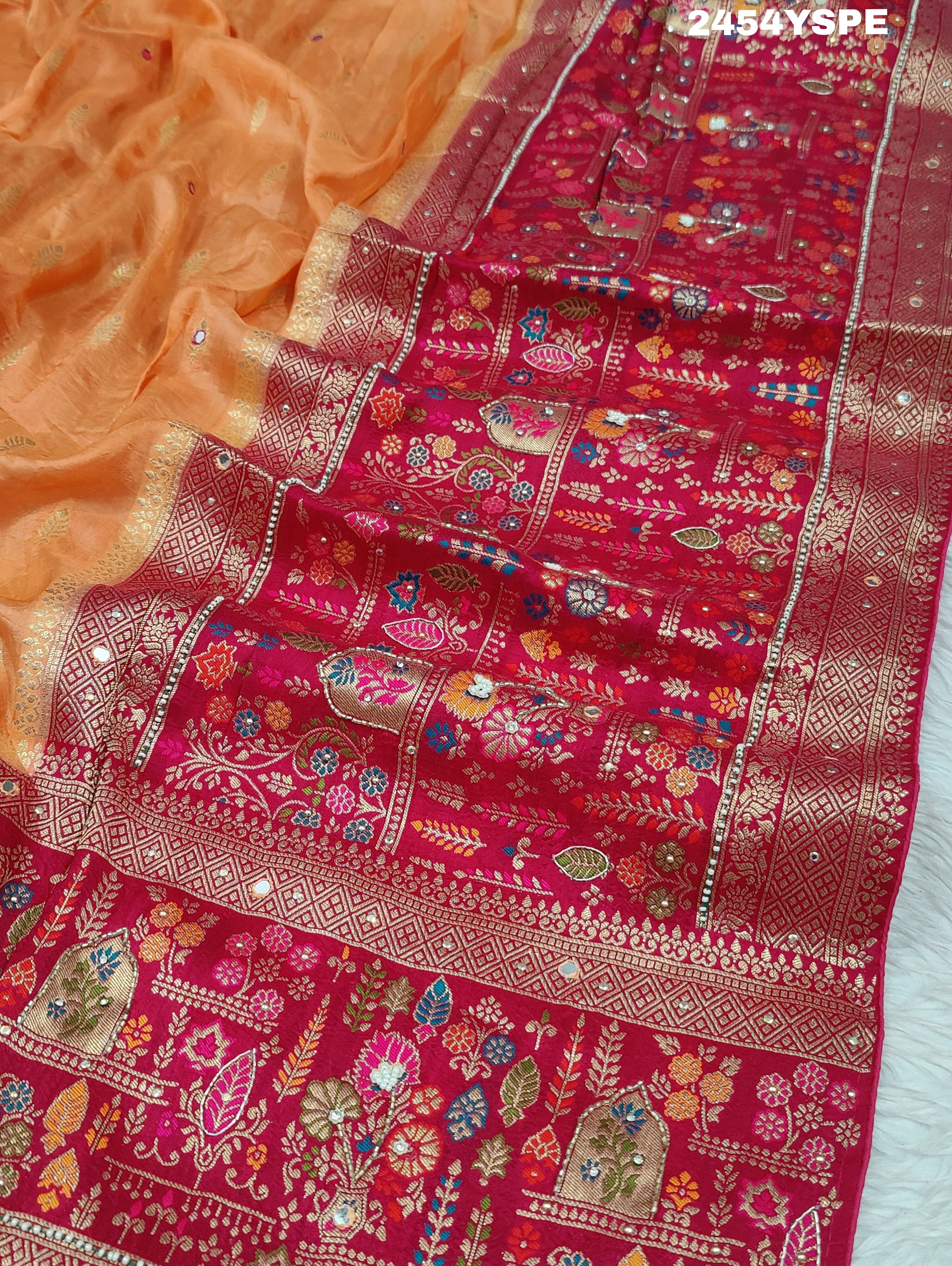 A Banarasi style saree with peach color and cutdana work, accompanied by a red and gold patterned border.
