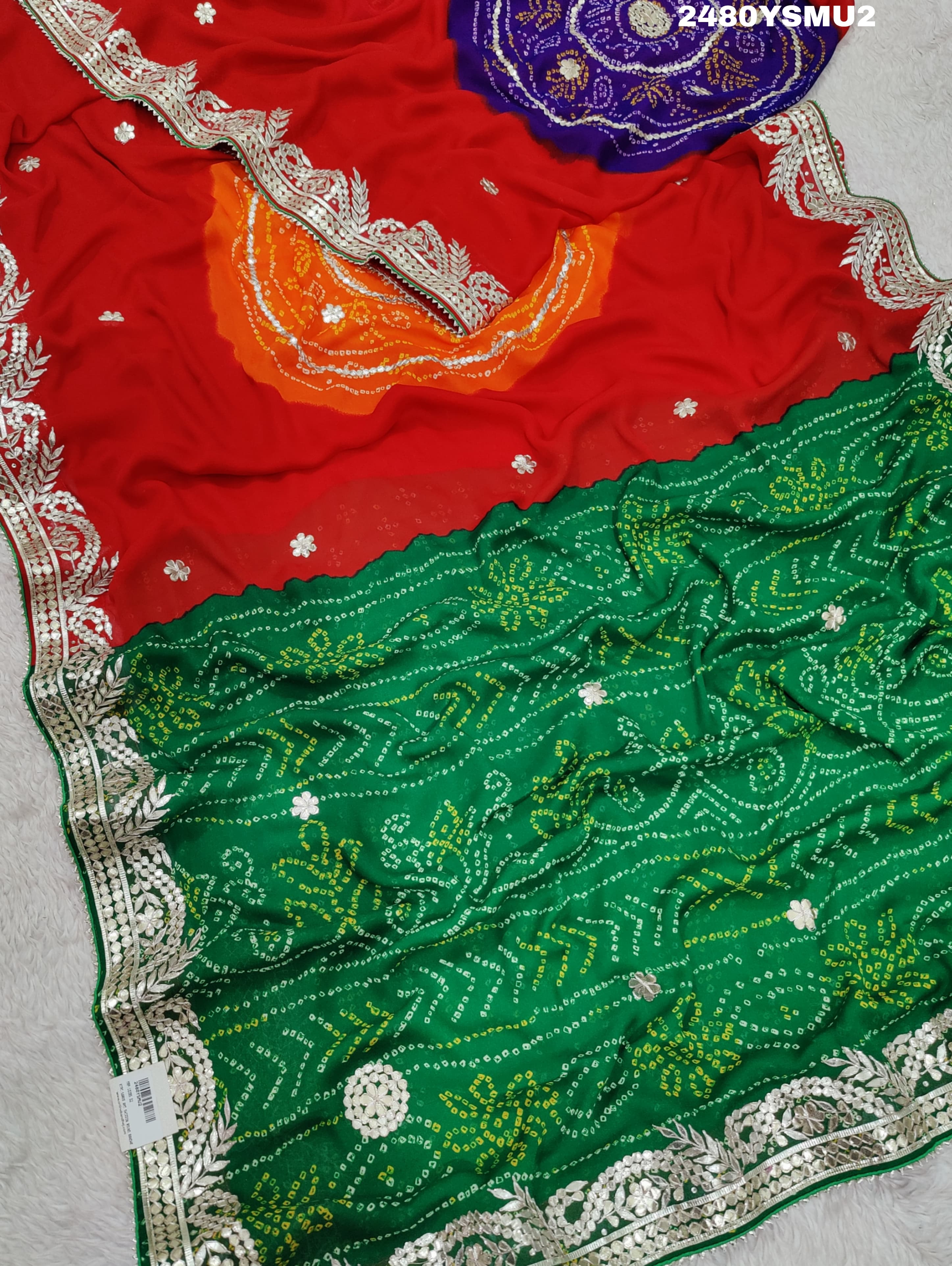 A saree with bandhani style patterns in red and green colors, featuring detailed gotapatti work.