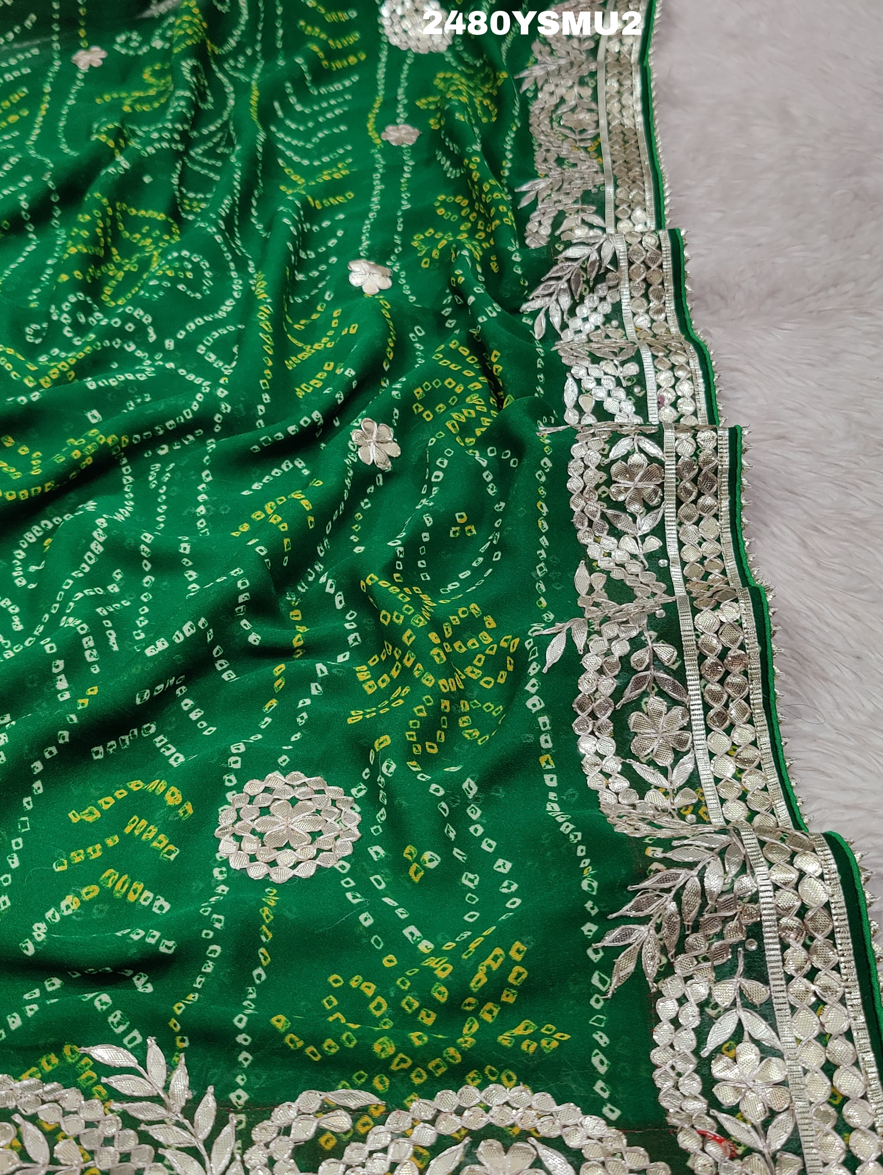 A saree with bandhani style patterns in red and green colors, featuring detailed gotapatti work.