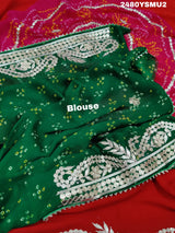 A saree with bandhani style patterns in red and green colors, featuring detailed gotapatti work.