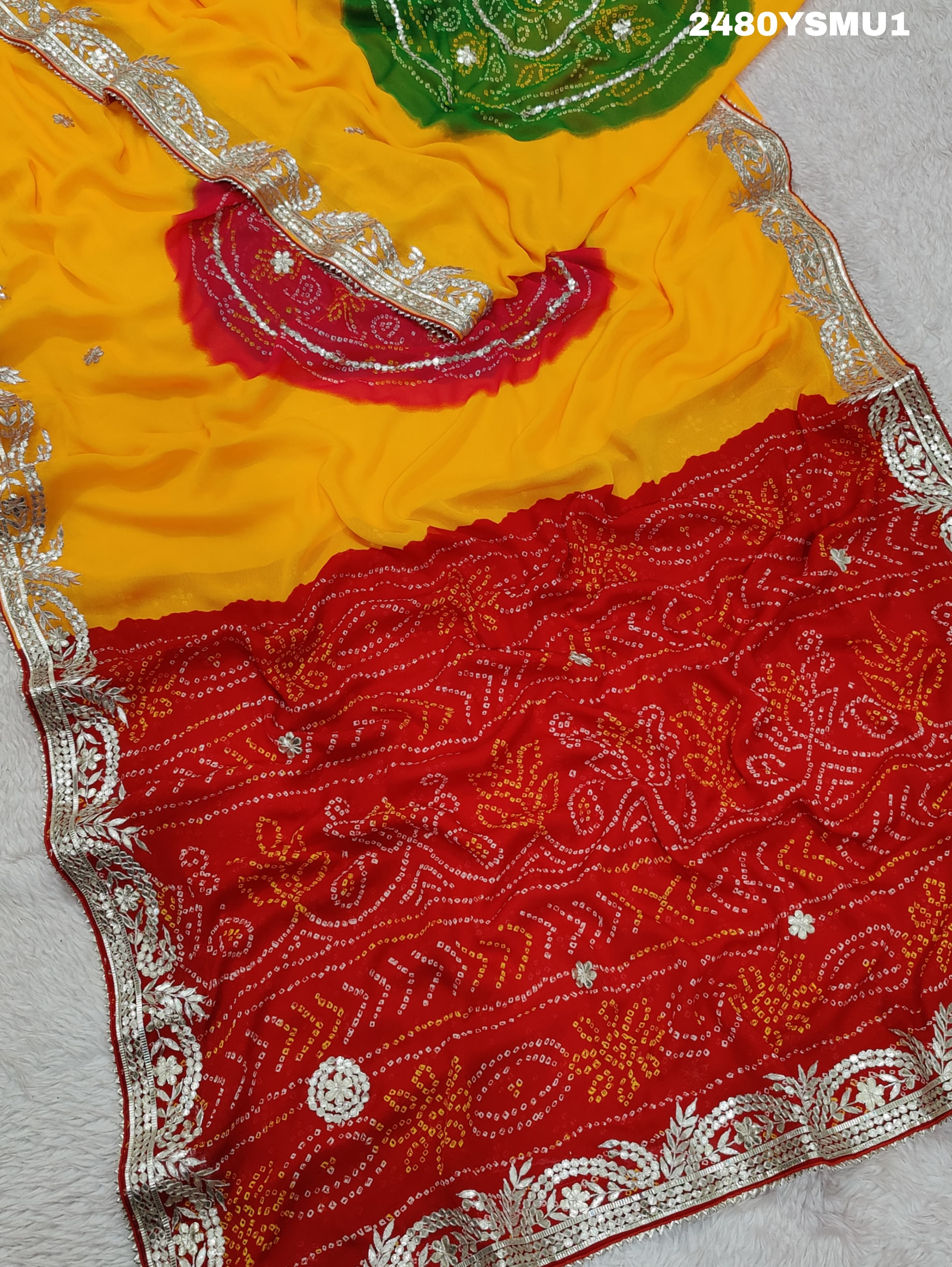 A saree with bandhani style patterns in orange and red colors, featuring detailed gotapatti work.