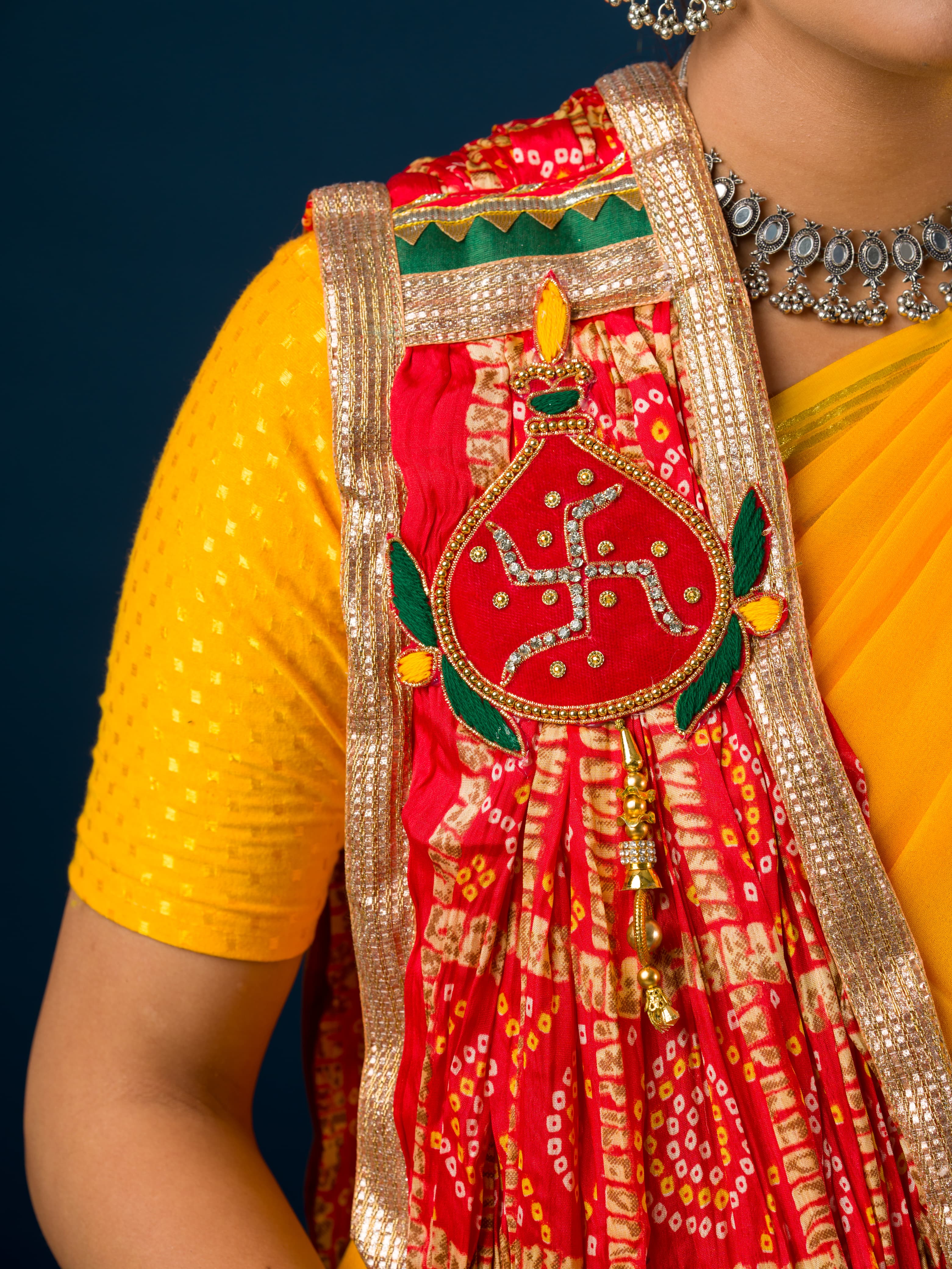 Atraditional Rajasthani Marwadi chunri pila with red and yellow colors, featuring heavy embellishments and a yellow border.