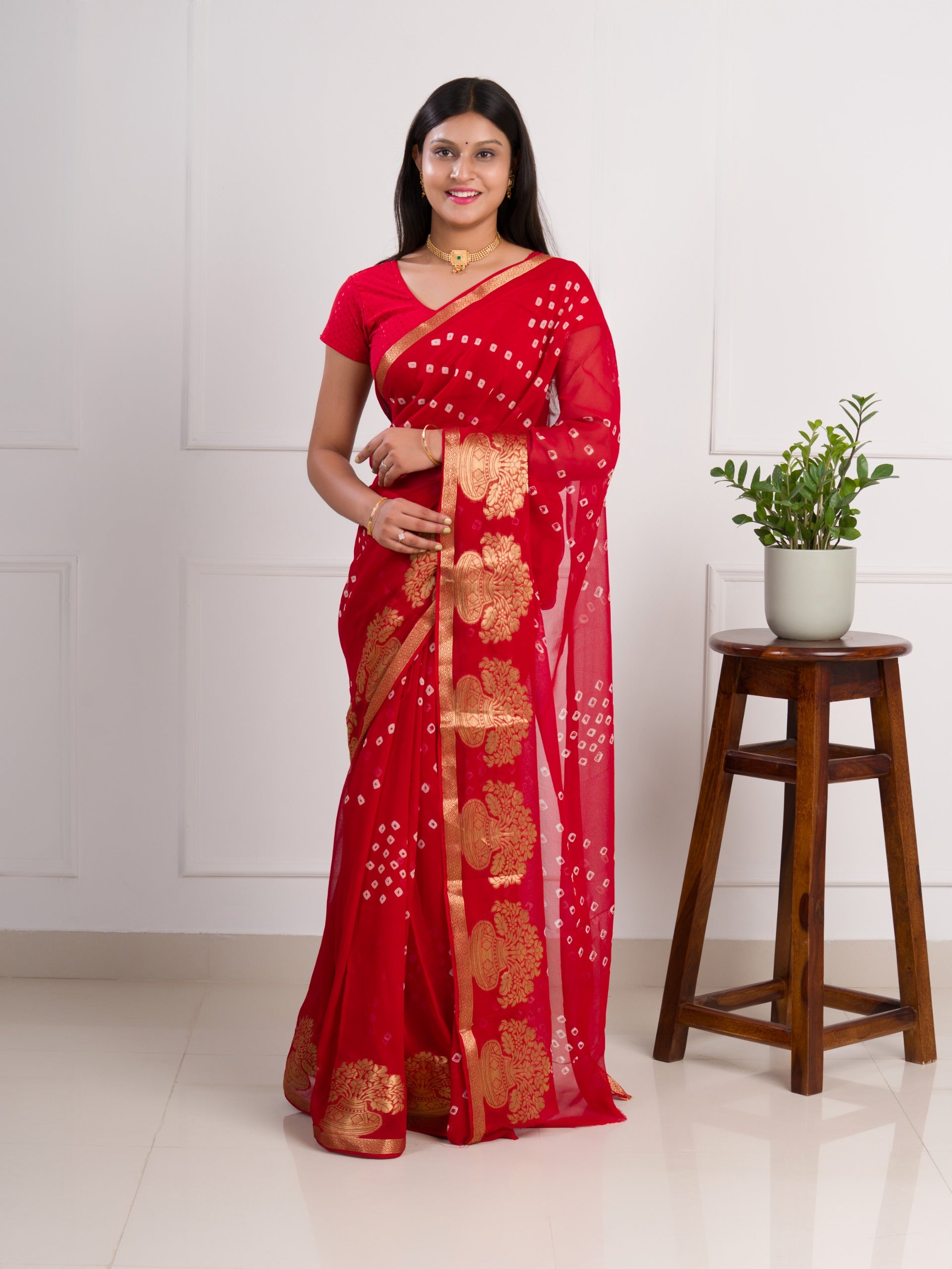 A red saree with gold patternsin Georgette Bandhani Style Saree