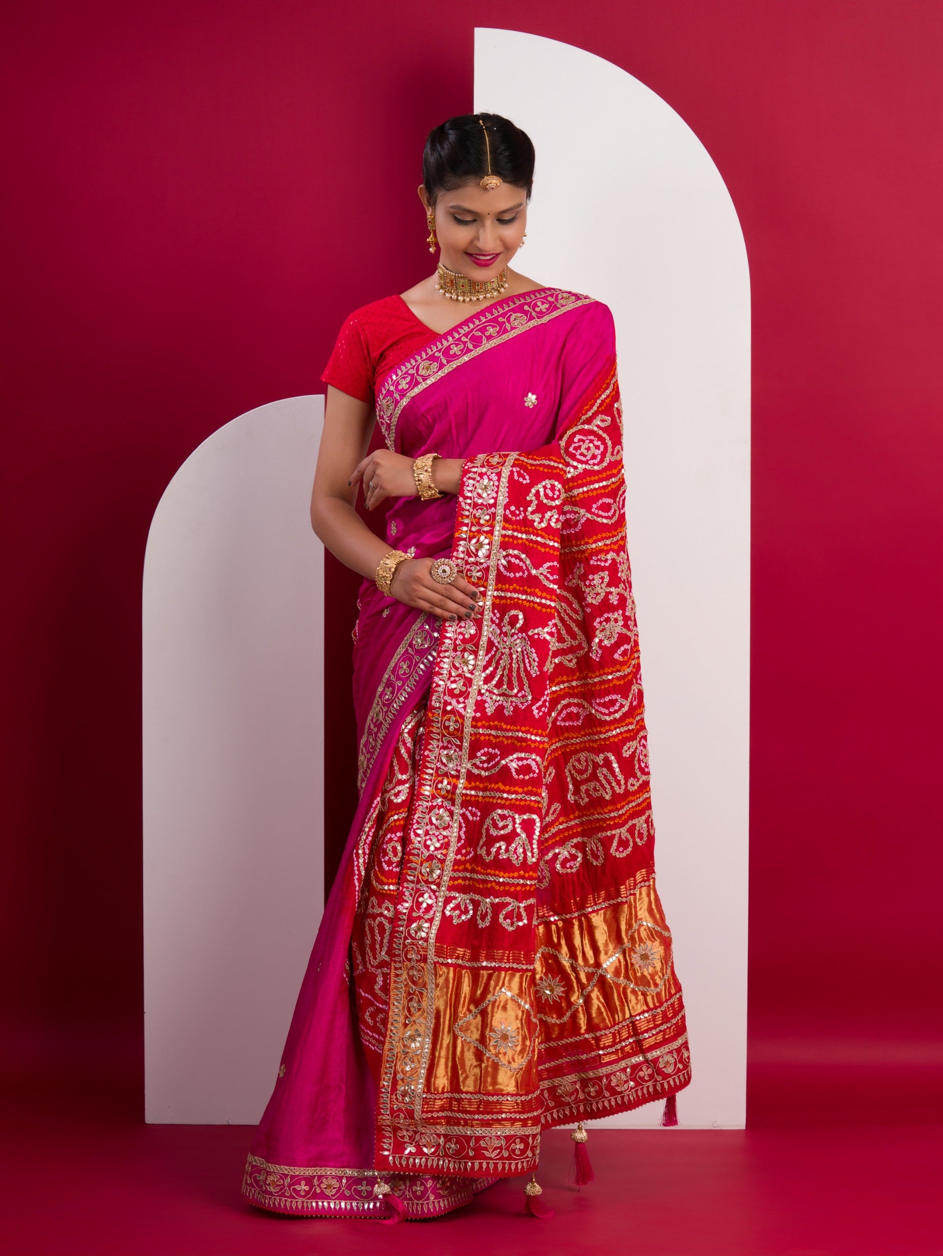 A pink saree with a red and gold border 
