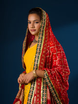 A woman modeling a red and yellow Banarasi Ojaria Chunri Piliya dupatta with a geometric pattern.