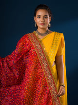 A woman modeling a red and yellow traditional dupatta with embroidery border