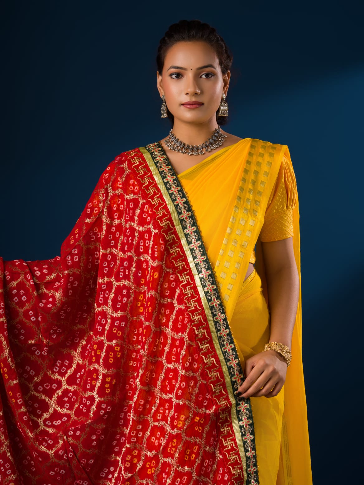 A woman modeling a red and yellow Banarasi Ojaria Chunri Piliya dupatta with a geometric pattern.